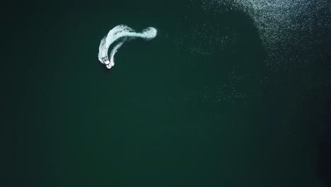 Aerial-bird-view-of-a-speedboat-riding-in-a-circle-and-making-beautiful-round-path-in-the-sea