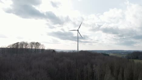 turbina eólica girando rápido detrás de un bosque oscuro y seco en el oeste de alemania