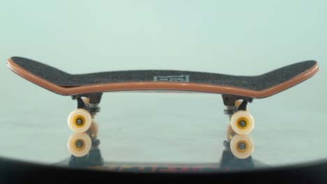 a beautiful detailed close-up shot of a mini skateboard, tiny white wheels, fingerboard on a shiny stand, mirror reflection, professional lighting, cinematic 4k video tilt up