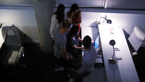 Team-of-executives-discussing-over-laptop-at-desk