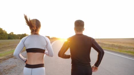 couple running on a road at sunset