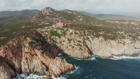 faro di capo spartivento, sardinia: wonderful aerial view in orbit over the majestic coast attacked by waves and the beautiful lighthouse