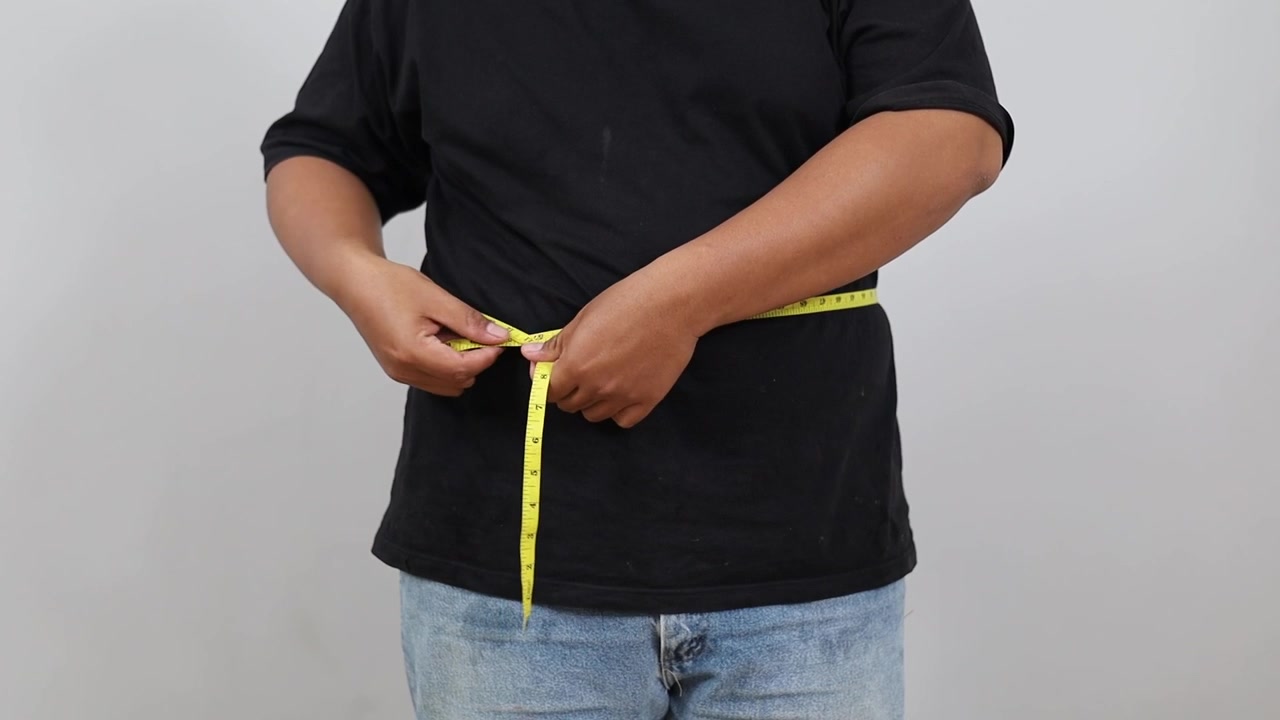 Overweight Asian man measuring waist with measure tape. Weight loss, motivation, fat burning