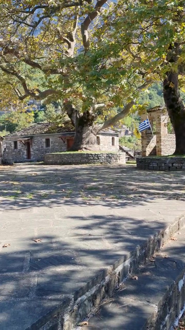 Scenic View of Traditional Stone Church and Ancient Plane Trees in Papigko Village, Zagori, Epirus, Greece. Beautiful Mountain Landscape and Old Greek Architecture in Autumn.
