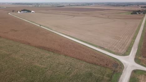 aerial view of truck driving way from the intersection of two gravel roads in rural iowa