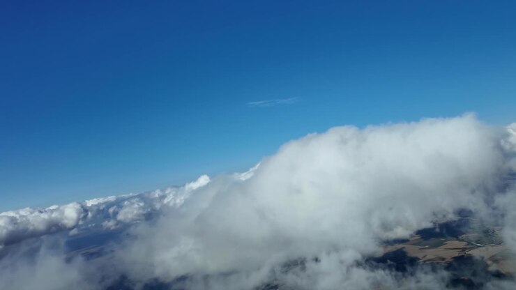Fordybende pilotperspektiv flyvende gennem bløde hvide skyer på en pragtfuld blå himmel.
