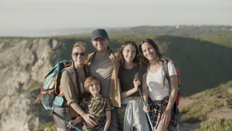 front view of a happy family standing on cliff and smiling at the camera