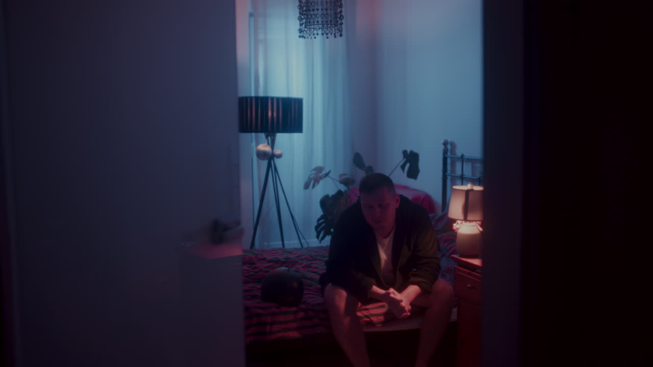 Man sitting in a dimly lit bedroom