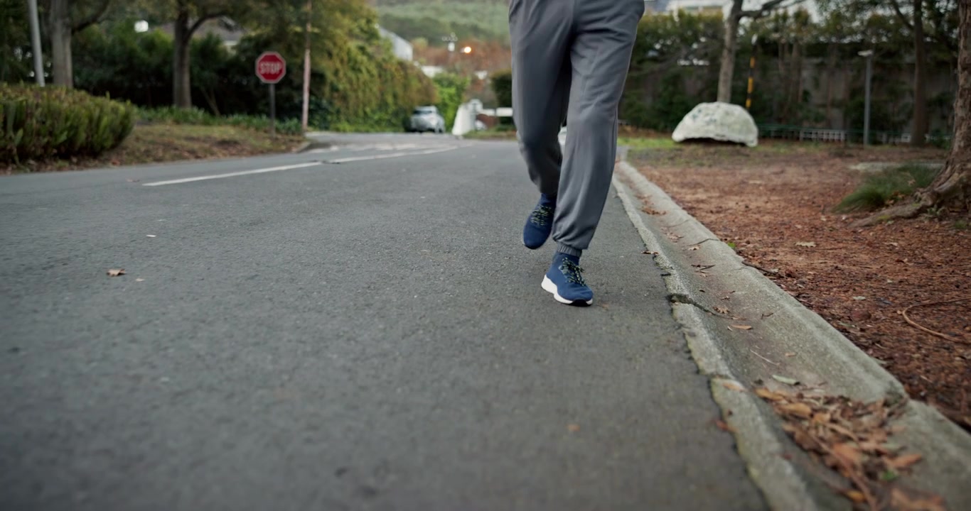 Uomo che fa jogging su una strada di periferia in abbigliamento sportivo