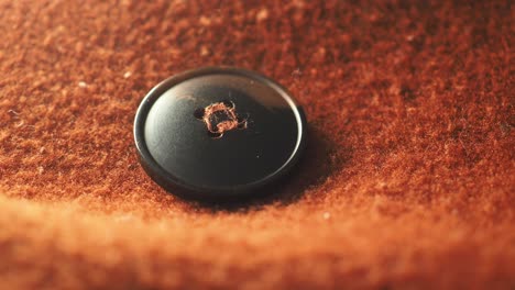 close-up of a black button on brown fabric