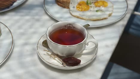 A-cup-of-tea-beside-a-delicious-breakfast-in-fancy-restaurant-close-up-shot,-high-angle-shot