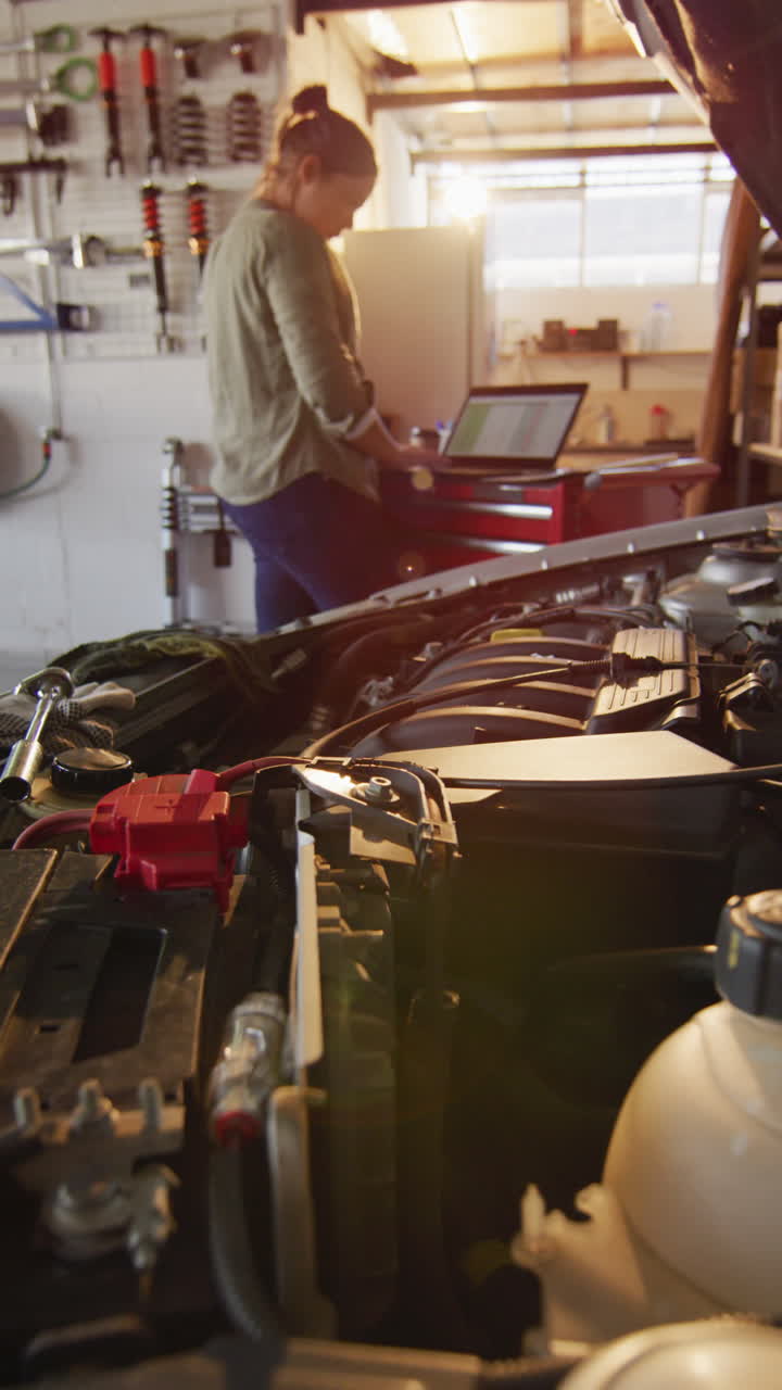 video vertical de una mecánica de automóviles caucásica usando una computadora portátil