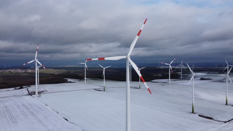 aerial orbiting view of a wind farm in rural winter landscape during cloudy day outdoors in nature