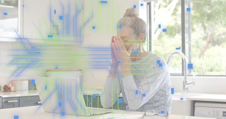 Woman in kitchen reviewing documents on laptop, initiating data overlays then receiving coffee mug