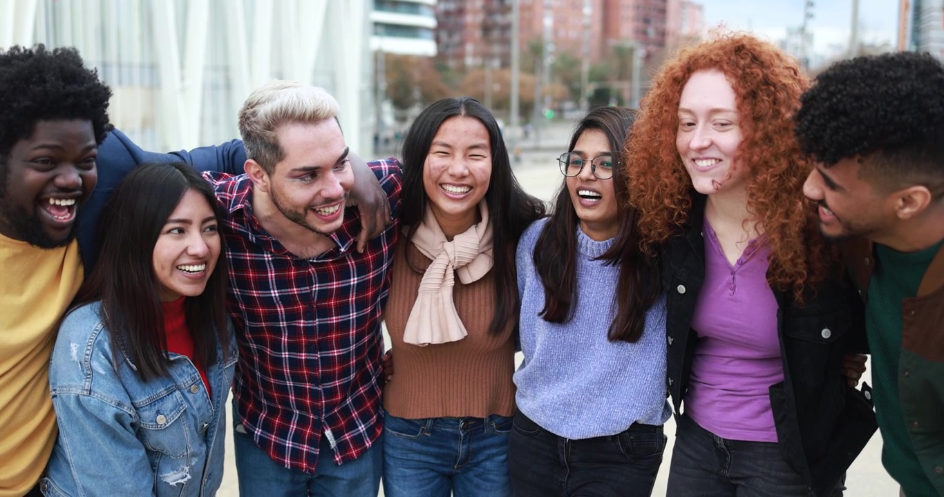 Gruppo eterogeneo di giovani amici che ridono insieme all'aperto