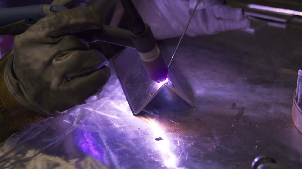близкий снимок сварщика в защитных перчатках, работающего на заводе