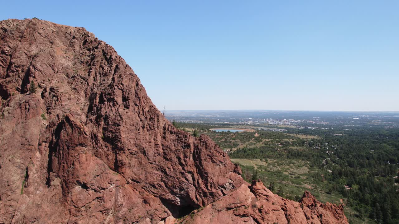 A view of the city in the distance from behind a high, rocky mountain.