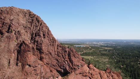 a view of the city in the distance from behind a high, rocky mountain.