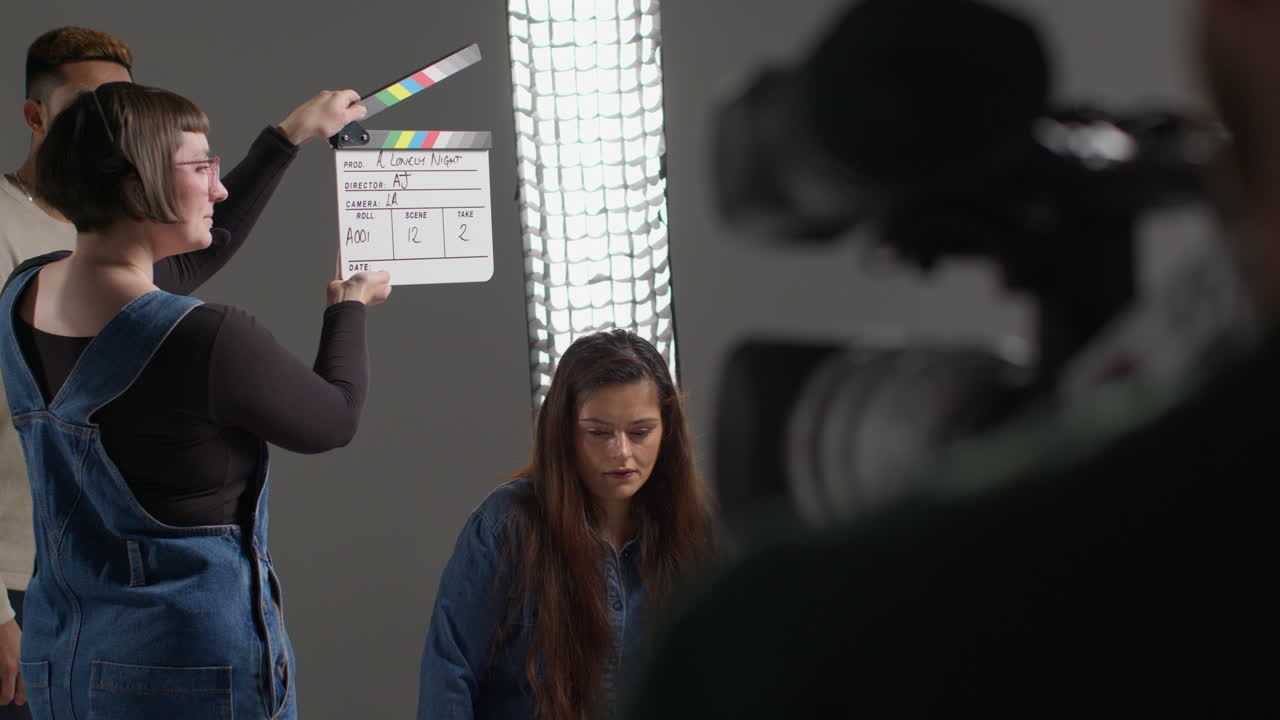 asistente femenina en el set de la película en el estudio usando clapperboard o pizarra en la película o video como actores comienzan la escena