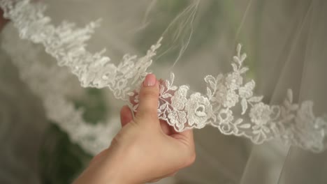 the bride strokes a white veil with her hands