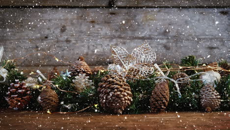 video composition with falling snow over desk with many pine cones