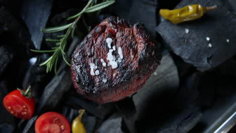 grilled steak on charcoal grill with rosemary and tomatoes