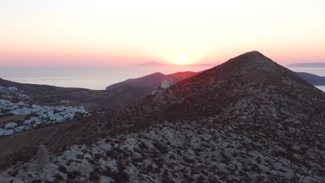 aerial flying mountain hill towards picturesque panagia church at stunning sunset, folegandros island