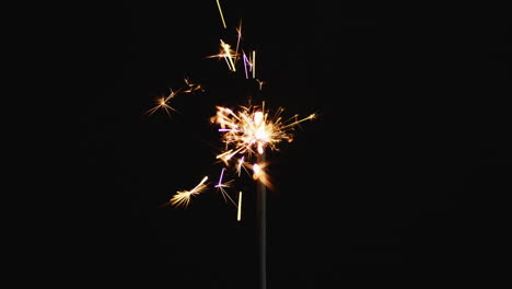 lit party sparkler sparkling on black background