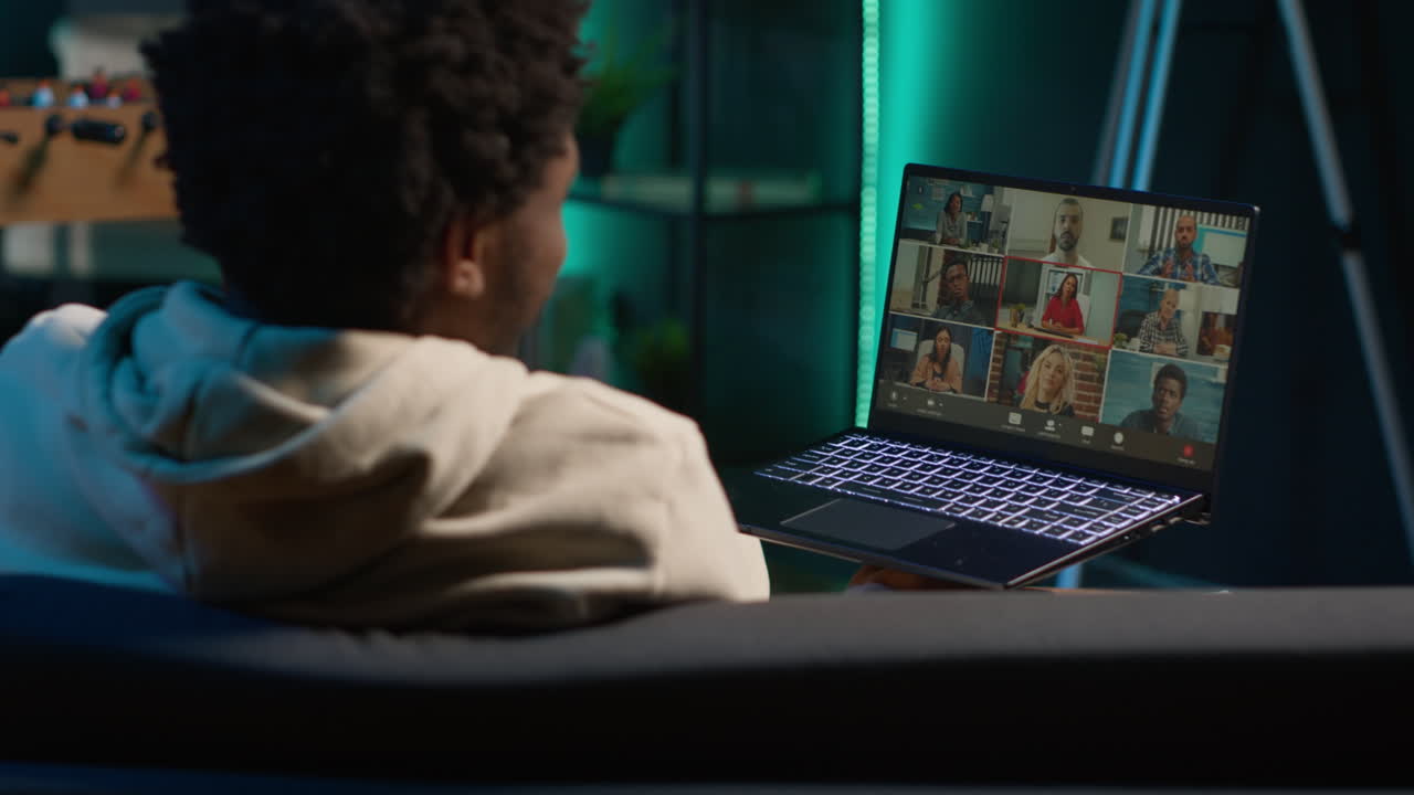Confident male speaker greeting colleagues on a video conference meeting, enjoying benefits of online remote communication in cozy loft. Young black adult hosting virtual discussion. Camera A.
