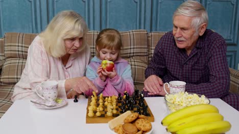 Älteres-Paar-Großvater,-Großmutter-Auf-Dem-Sofa-Ruhen,-Schach-Spielen-Mit-Enkelin-Kind-Kind