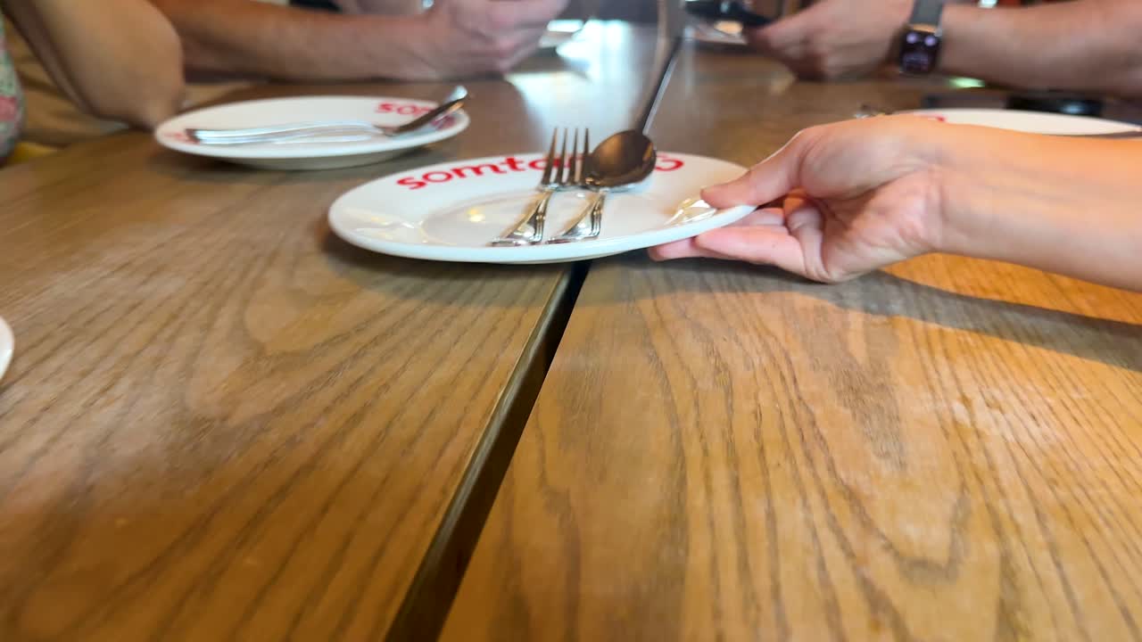 People use smartphones and pass a plate at a modern restaurant table with natural lighting