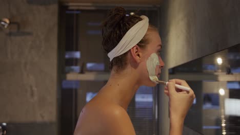 Caucasian-woman-putting-on-face-mask-in-hotel