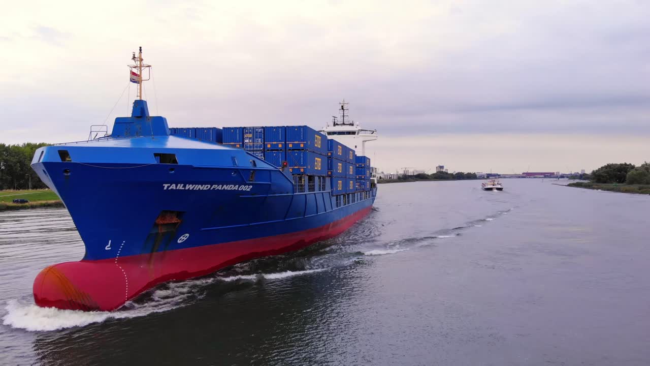 hermoso barco panda con viento de cola cargado con contenedores azules en el río oude maas, países bajos