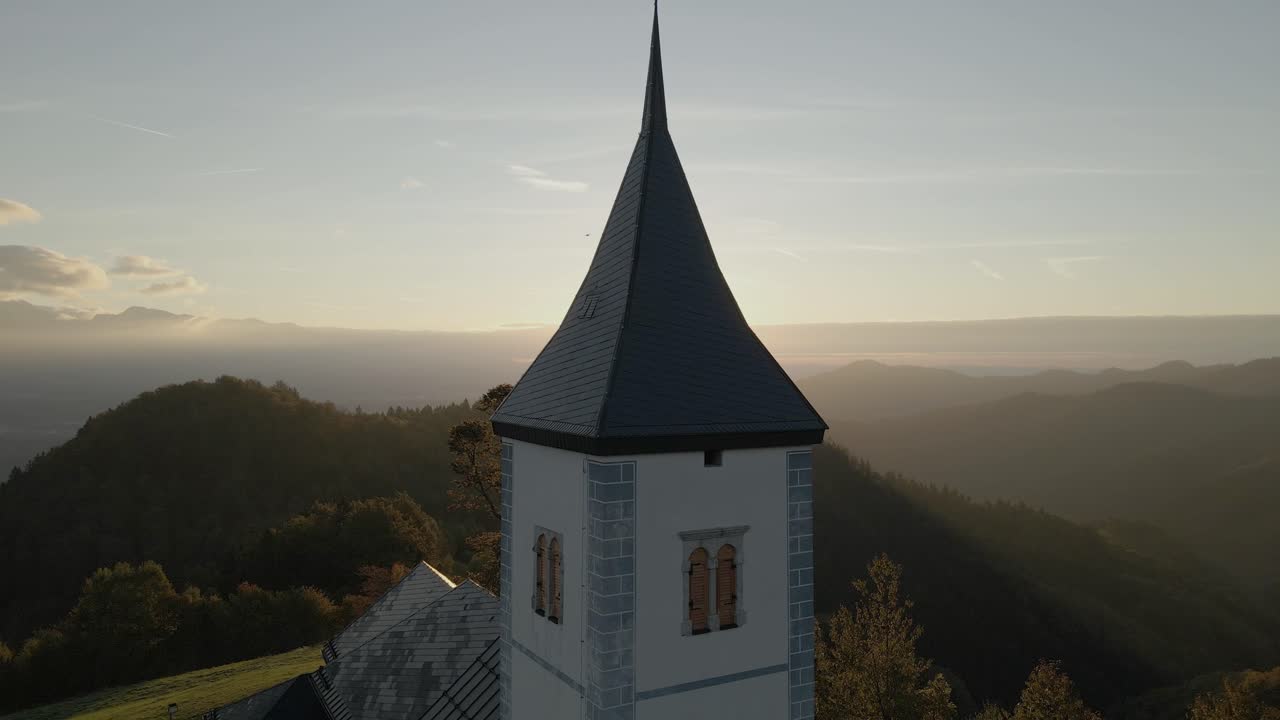 Kirche St. Primoz, vom Morgenlicht beleuchtet, auf einem Hügel mit Berglandschaft, Jamnik, Slowenien