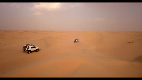 Aerial-view-of-two-trucks-on-an-extreme-dune-bashing-competition-in-the-desert