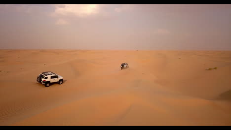 aerial view of two trucks on an extreme dune bashing competition in the desert