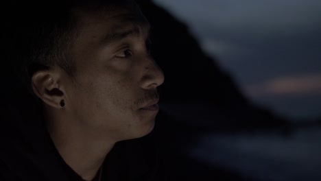 Young-Nepalese-man-sitting-alone-on-beach-smoking-cigarette-at-night