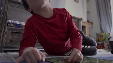 ground view of caucasian kid, playing classic board game snakes and ladders on the carpet at home