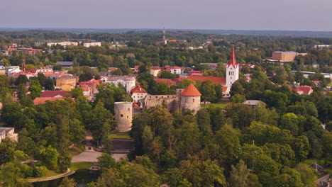 aerial establishing left of cesis, latvia, showcasing a historic town center surrounded by lush greenery and slight haze in air