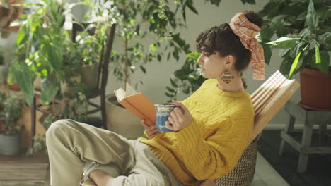 woman reading book and having tea in home garden