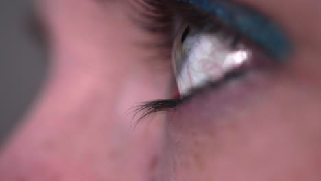 close up on woman eye looking at a smartphone, digital screen reflecting on eye - macro shot