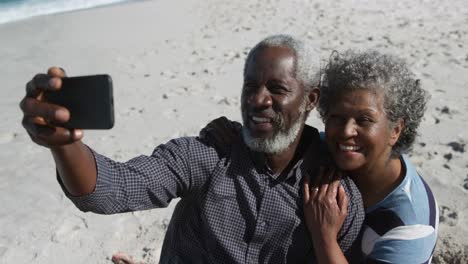 senior couple taking photos at the beach