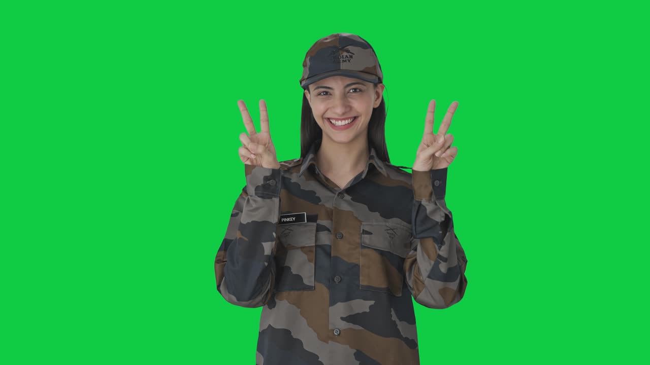 feliz mujer india oficial del ejército mostrando el signo de la victoria pantalla verde
