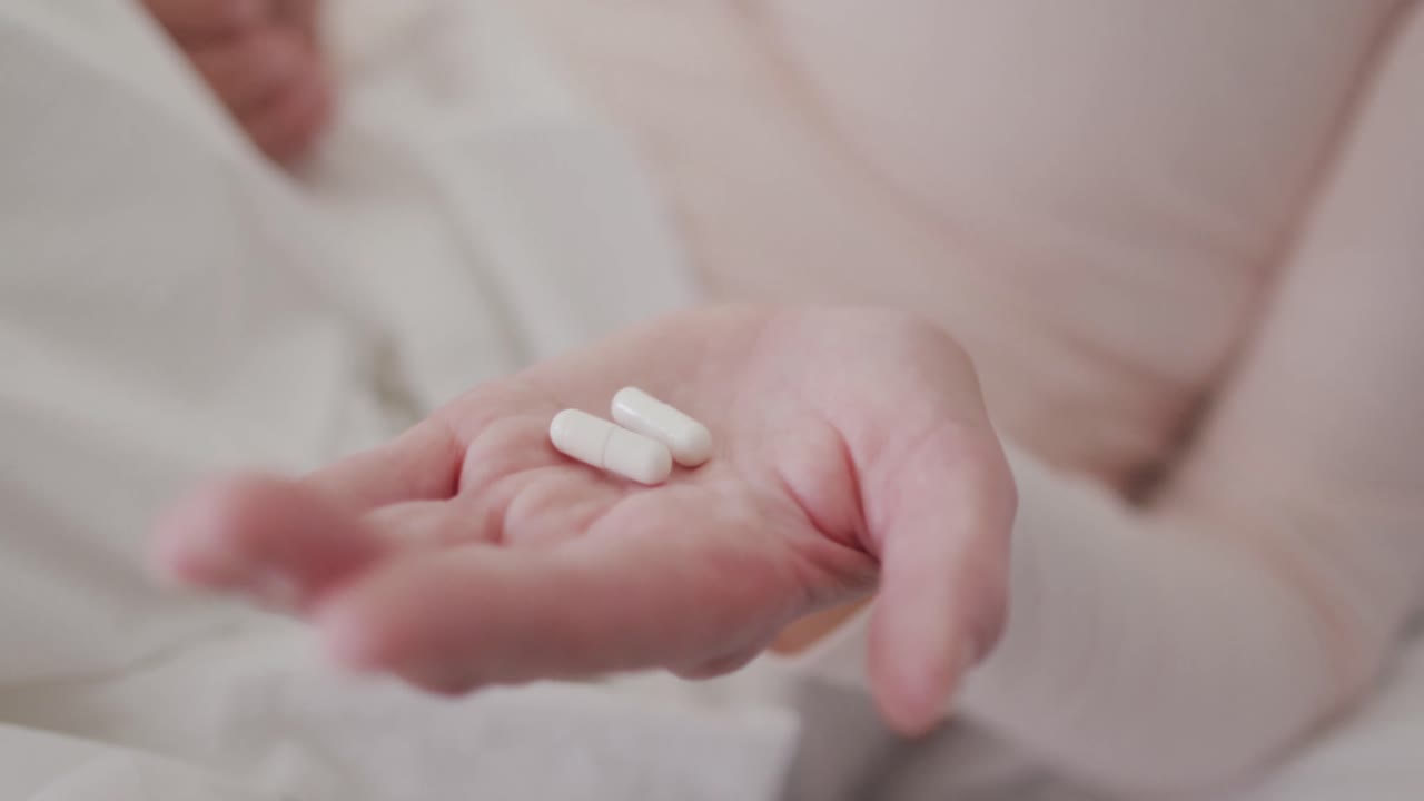 Primo piano di donna che tiene delle pillole in mano.
