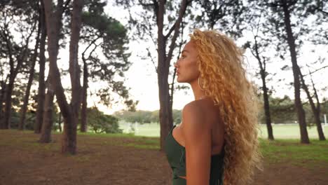 a beautiful woman walking alone the forest with peaceful trees during sunset - close-up shot