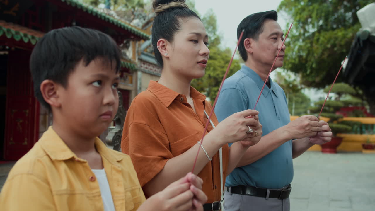 Son and Parents Saying Prayer with Burning Sticks