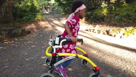 Niña-Negra-Con-Parálisis-Cerebral-Caminando-En-El-Parque-Con-Su-Dispositivo-De-Asistencia