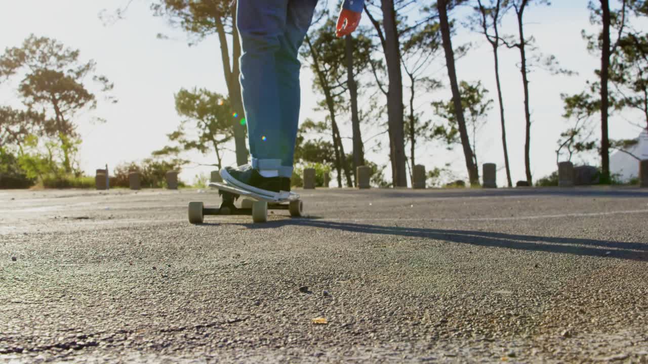 vista trasera de un joven patinador de sexo masculino montado en patineta en una carretera de campo 4k
