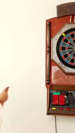 rear view of an african woman playing darts at home