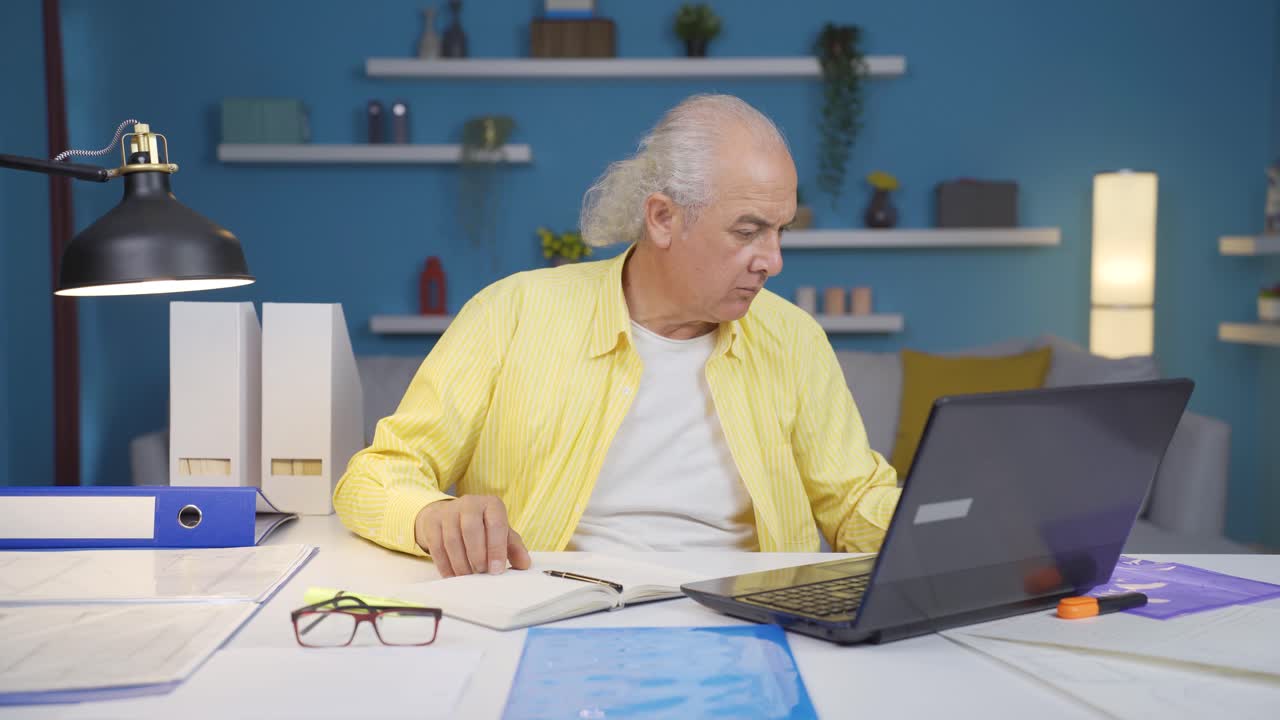 Home office worker old man finds what he is looking for on the table.